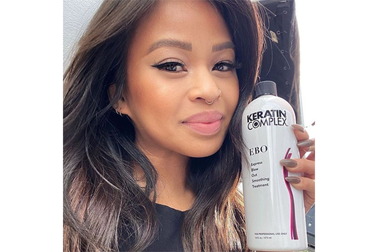 Close-up of a woman showing a bottle of keratin complex