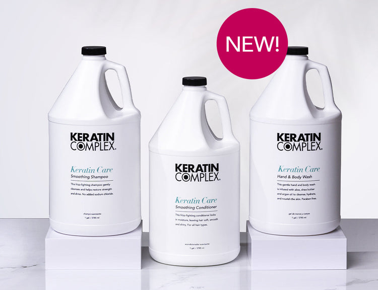 New large bottles of Keratin Complex Keratin Care products, including Smoothing Shampoo, Smoothing Conditioner, and Hand & Body Wash, displayed on white pedestals.