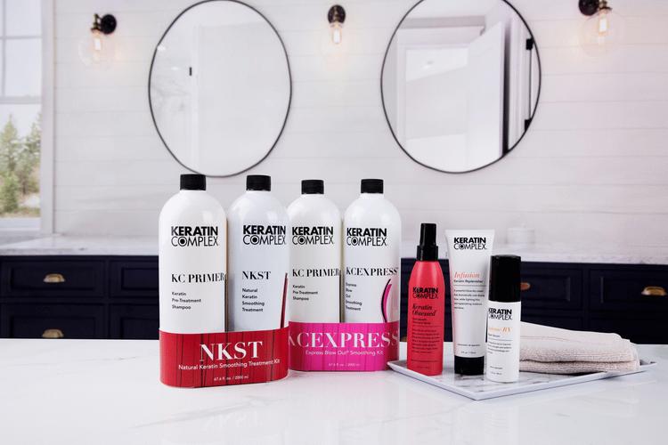 Keratin Complex NKST, KC PRIMER, and EXPRESS treatments, along with styling products, displayed on a white countertop in a modern bathroom setting.