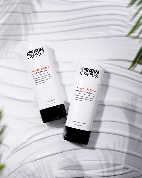 Keratin Volume Amplifying Shampoo and conditioner bottle on a white textured background