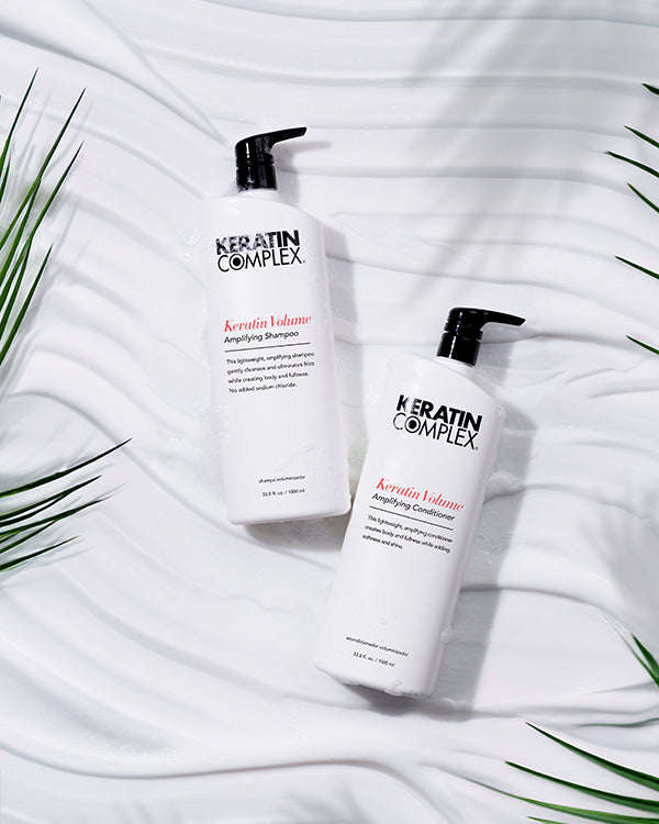 Keratin Volume Amplifying Shampoo and conditioner liter bottle on a white textured background