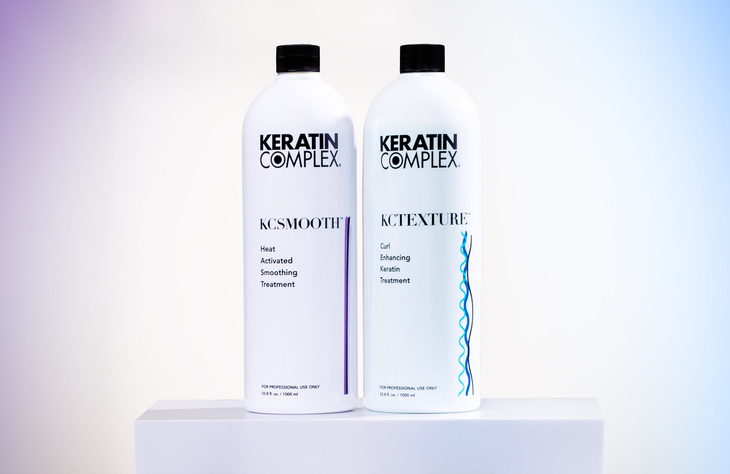 Two white bottles of Keratin Complex hair treatment products on a light-colored platform.
