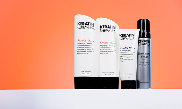 A collection of Keratin Complex products arranged on a white countertop, including sprays, lotions, and foams.