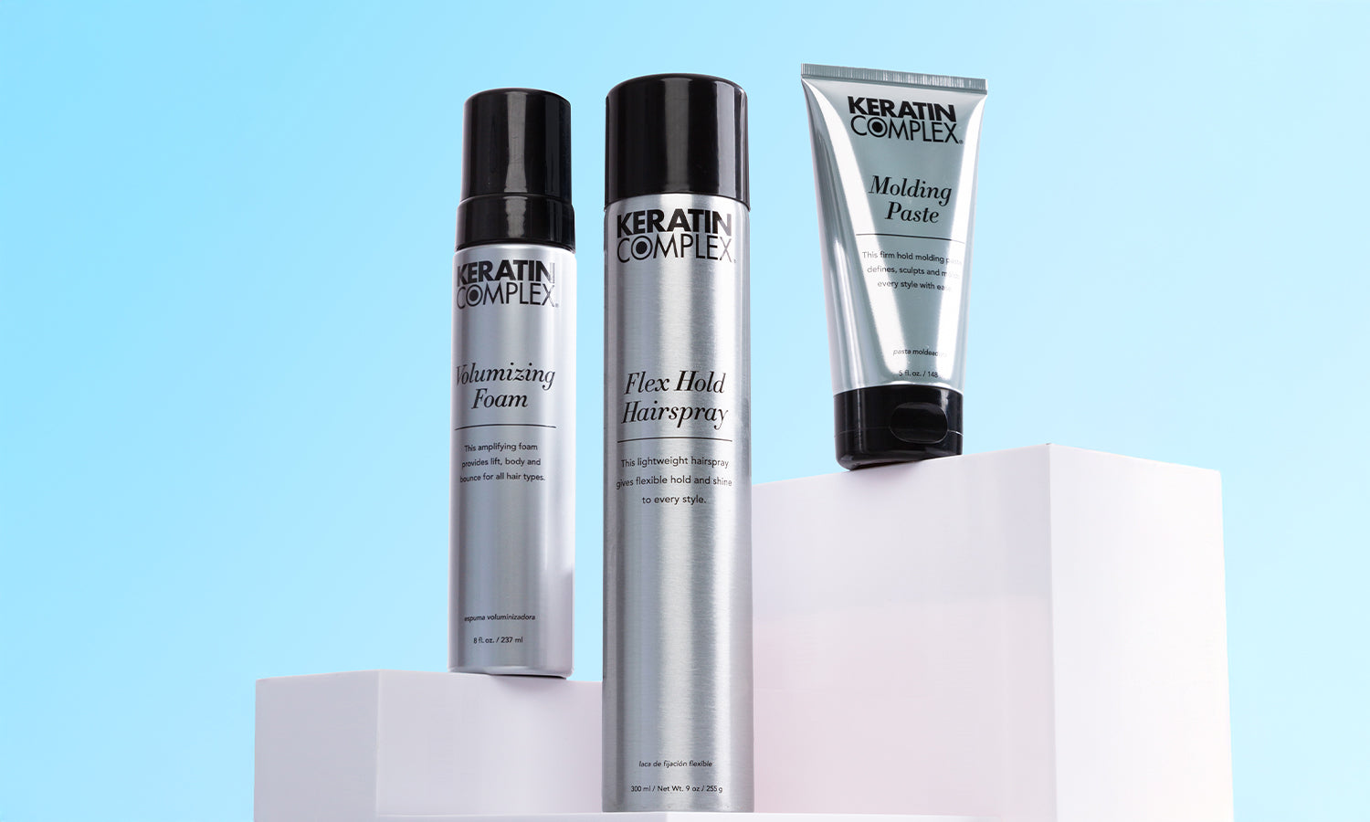 Keratin Complex styling products displayed on white podiums against the blue background.