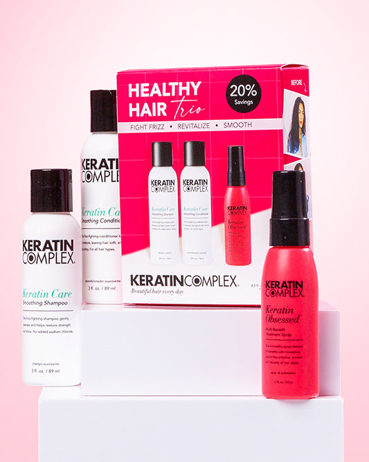 Healthy Hair Trio product set displayed on white blocks against a light pink background, featuring three hair care products