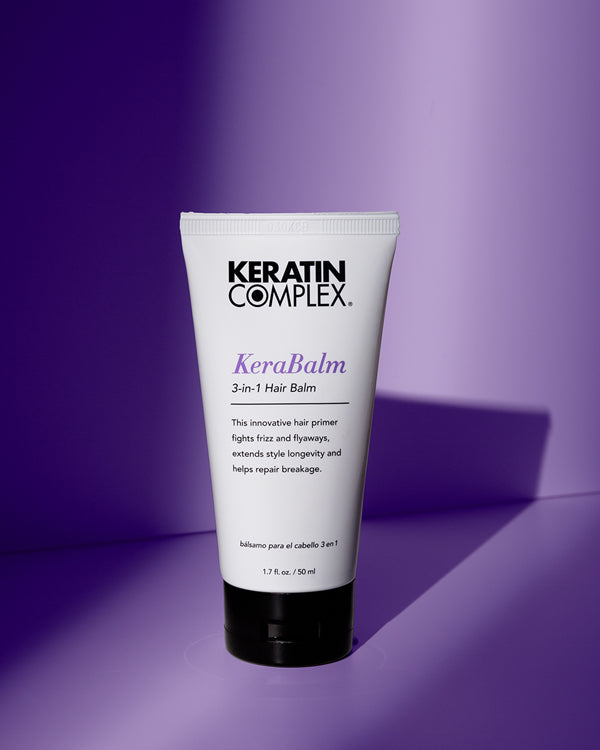 A bottle of KERABALM on a purple background The lightweight primer features a sleek design with a label showcasing its frizz-fighting and styling benefits.