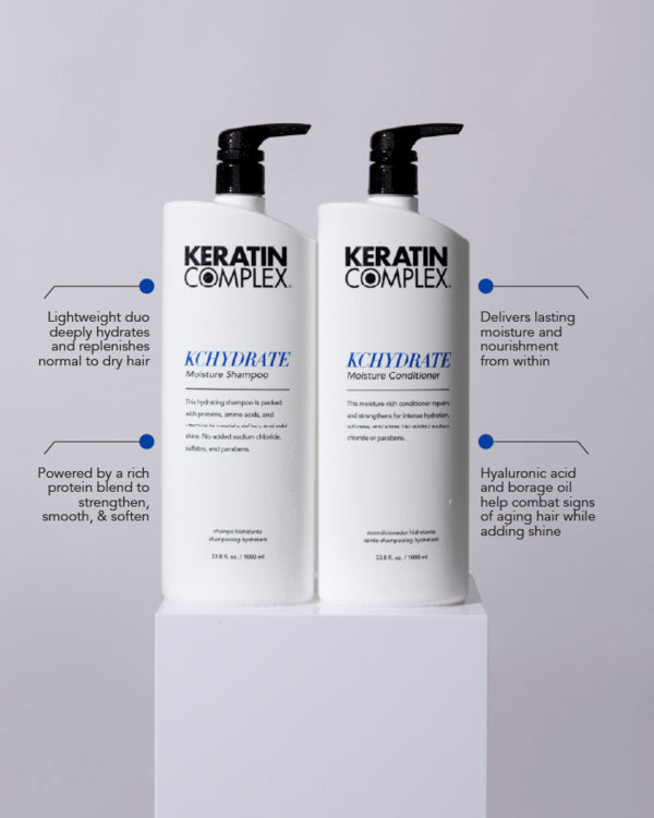Two bottles of Keratin Complex KCHYDRATE hair care products, including Moisture Shampoo and Moisture Conditioner, are displayed on a white pedestal. Text annotations appear around the bottles with product benefits: ｜Lightweight duo deeply hydrates and replenishes normal to dry hair｜, ｜Powered by a rich protein blend to strengthen, smooth, & soften｜, ｜Delivers lasting moisture and nourishment from within｜, and ｜Hyaluronic acid and borage oil help combat signs of aging hair while adding shine｜