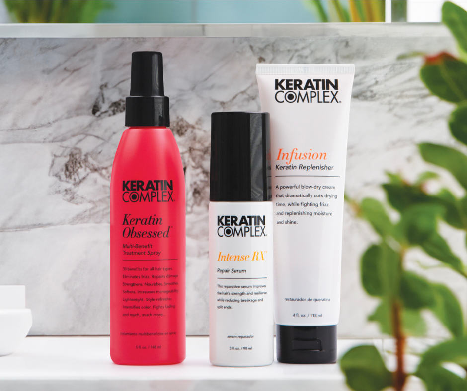 Three Keratin Complex products displayed on a marble surface with greenery in the background. 