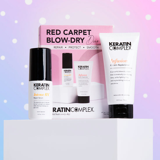 Red Carpet Blow Dry Duo set against a soft holiday-themed background with pink and purple hues and snow-like dots.