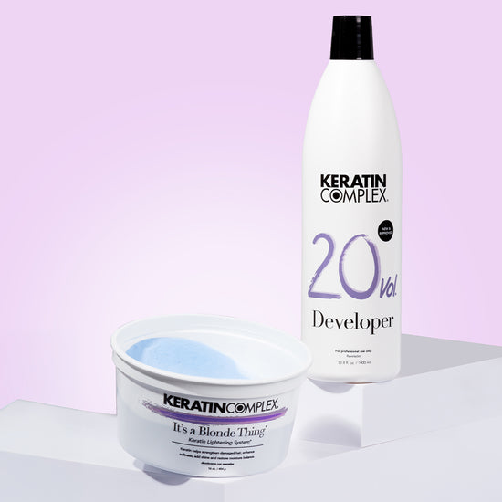 Keratin Complex 'It's a Blonde Thing' Keratin Lightening System and 20 Vol. Developer bottle displayed against a soft gradient background.