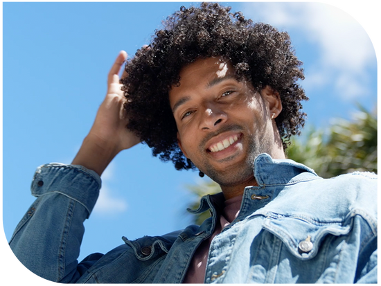 Diverse young man holding curly hair wearing a jeans jacket 
