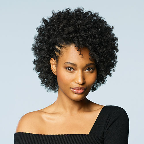 A closeup of a woman with short black curly hair, she has on a black top